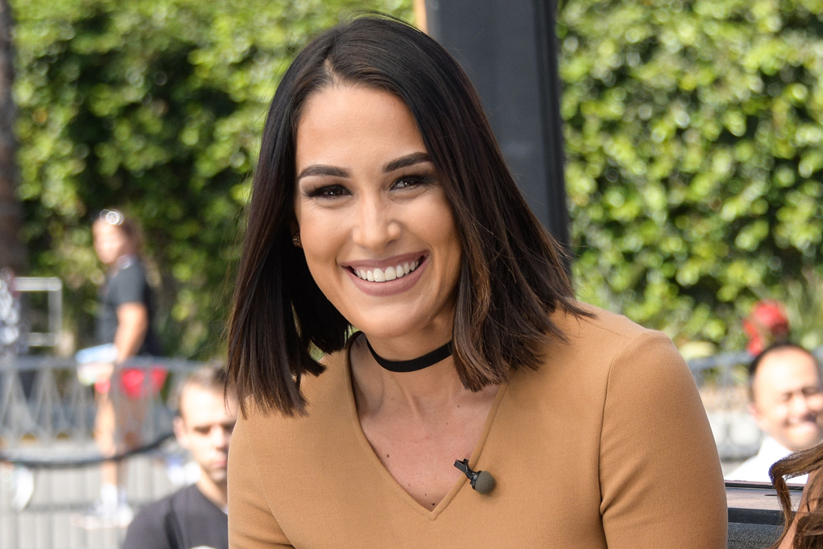 Nikki Bella touches her growing bump as she puts on loved-up