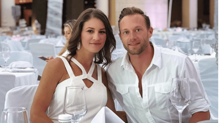 Danielle wearing white with her husband, Adam Busby, also wearing white