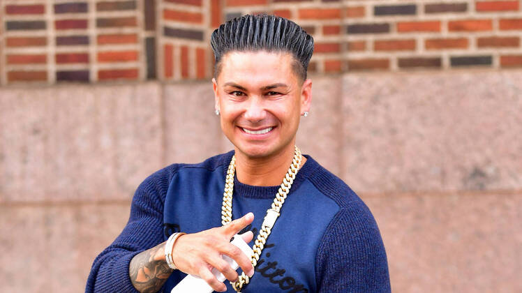 Pauly D Wearing a Blue Sweater With a Chain Around His Neck
