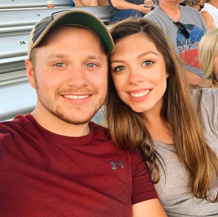 josiah and lauren duggar smiling at the camera sitting on bleachers