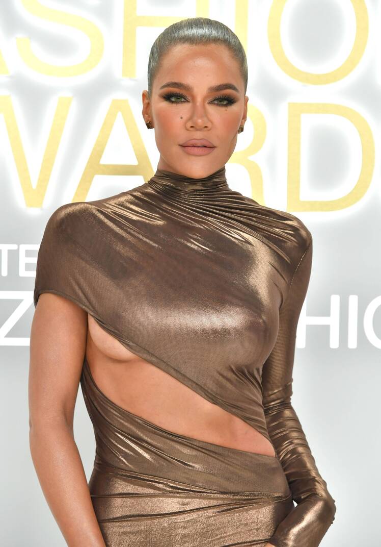 Khloe Kardashian poses in a gold cutout gown