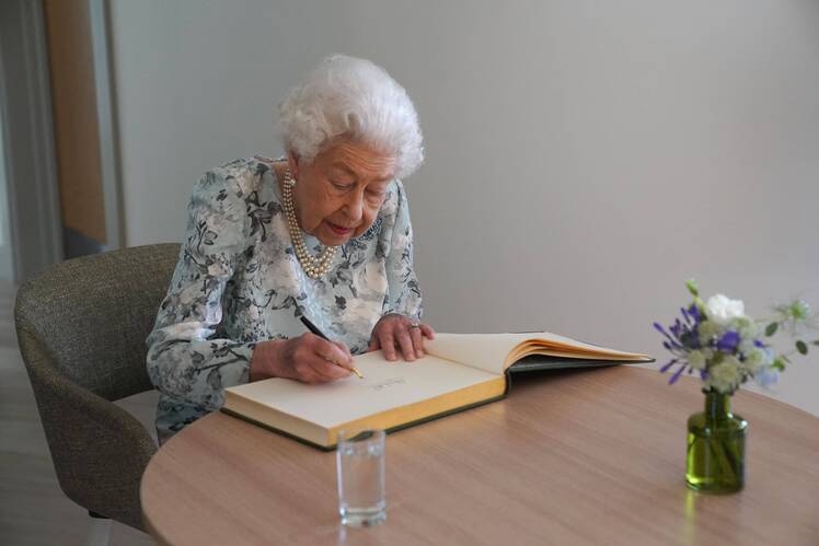 Queen Elizabeth II signs a guestbook