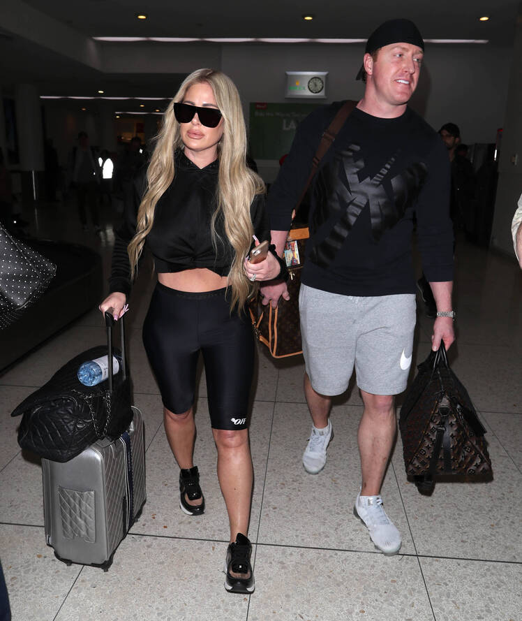 Kim Zolciak wearing black biker shorts and a black top while walking next to Kroy Biermann in gray shorts and a black shirt.