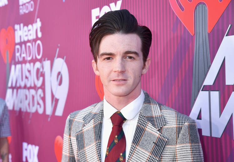 Drake Bell wearing a plaid suit and burgundy tie