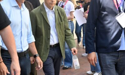 Rick Moranis walks out of a building surrounded by men.
